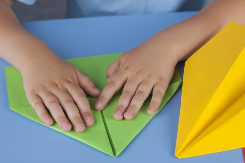 Child folding a green paper airplane at the McChord Air Museum.